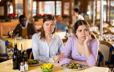 Woman calming her female friend down in restaurant because she's feeling depressed.