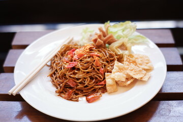 instant noodles with a very spicy taste as a favorite food in Indonesia. red noodles with mixed spices and chili. spicy food on a white plate on a blurred background