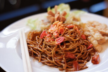 instant noodles with a very spicy taste as a favorite food in Indonesia. red noodles with mixed spices and chili. spicy food on a white plate on a blurred background