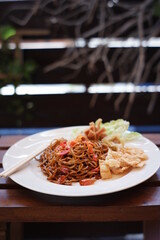 instant noodles with a very spicy taste as a favorite food in Indonesia. red noodles with mixed spices and chili. spicy food on a white plate on a blurred background