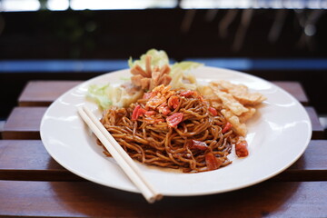 instant noodles with a very spicy taste as a favorite food in Indonesia. red noodles with mixed spices and chili. spicy food on a white plate on a blurred background