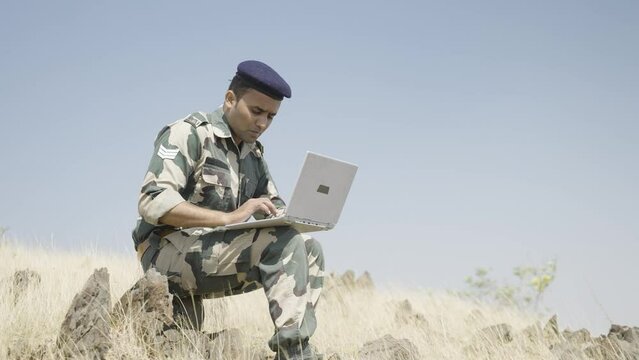 soldier busy using laptop on top of mountain