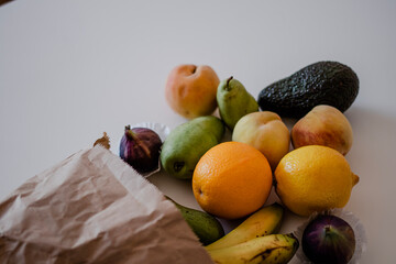 Different fruits in a crafted paper bag on the table. Healthy flat lay