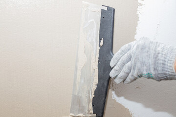 Man plastering wall with putty-knife, preparation for painting.Hands of worker with wall plastering tools renovating house. Plasterer renovating walls and corners with spatula.Copy space