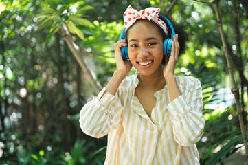 Portrait happy young woman with headphone in the garden	