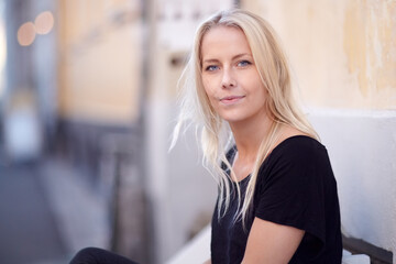 A natural beauty. Portrait of a beautiful young woman sitting on a bench on the street.