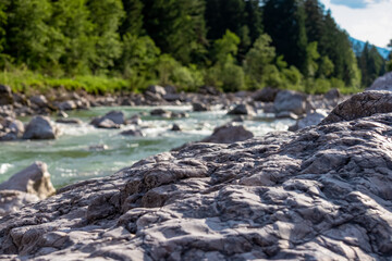River Gail flowing through the Schuett in the natural park Dobratsch in Villach, Carinthia, Austria. Gailtaler and Villacher Alps. Riverbank is full of massive rocks. Swimming in crystal clear water