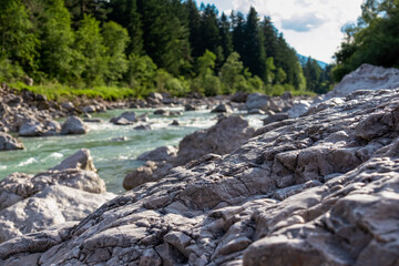 River Gail flowing through the Schuett in the natural park Dobratsch in Villach, Carinthia, Austria. Gailtaler and Villacher Alps. Riverbank is full of massive rocks. Swimming in crystal clear water