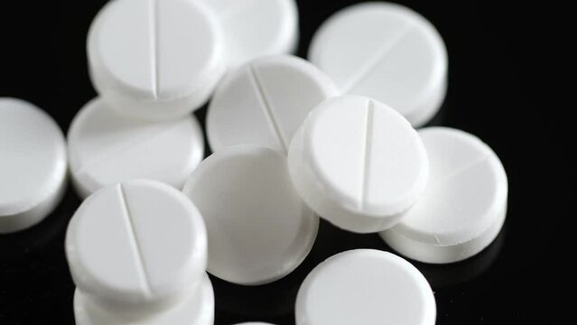 Many white round pills. Pharmaceutical production. Drugs on the production line. Moving background. close-up. view from above. white medical pills rotating closeup. Pills and drugs. Pharmaceutical