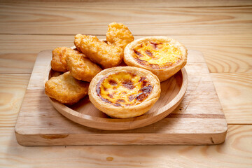 Fried chicken nuggets with egg tart on wooden background.