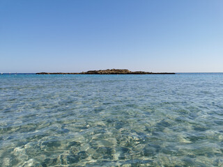 Fototapeta na wymiar Fig Tree Bay beach, crystal clear water, white sand at the bottom, small island off the coast.
