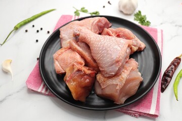 Clean and Raw Chicken on a black plate with Indian spices and cooking ingredients. Along with copy space. Chicken curry cut. Biryani cut chicken with skin on. complete animal based Protein source.