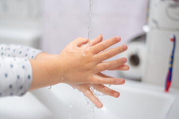 Child girl washing hands in the bathroom. Kid hygiene. People health care during the pandemic...