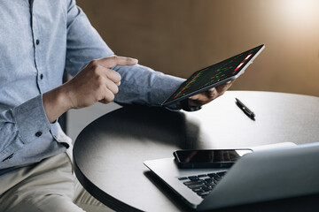 stock market profit analysis concept, risk management, financial freedom, male stock marketer using tablet to buy shares for profit using internet media to analyze profitable company data.