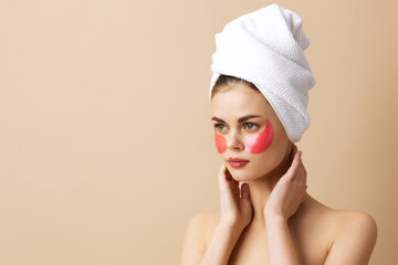 portrait woman pink patches on the face with a towel on the head beige background