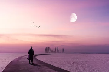 Fotobehang A lonely man is standing on a wooden pier and looking to the horizon with lilac sky and moon © Sondem
