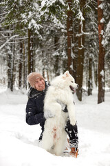 A human and a dog are best friends. Man and dog walk in snowy forest in winter in deep snow on a sunny day.