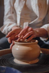 Women's hands are molding a cup of clay. Master class on the potter's wheel and the manufacture of clay products.