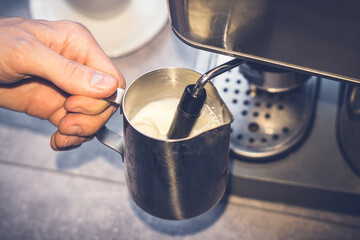 Cappuccino preparation. Barista beating milk in milk seller. Steamer. Coffee machine. Closeup