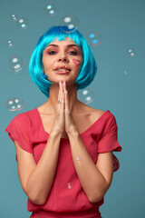 Beautiful young woman with blue wig and bright make-up in soap bubbles. Fashion model girl with creative color makeup. Women doll concept.