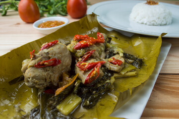 Steamed spicy chicken wrapped with banana leaf a.k.a Pepes Ayam in Indonesia, served with warm rice and chili sauce 