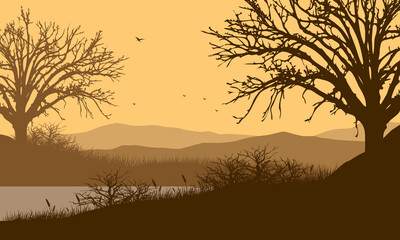 Beautiful mountain view with dry tree silhouette from the riverside at dusk