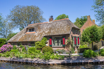 Fototapeta na wymiar Old house with colorful shutters in at the canal in Giethoorn, Netherlands