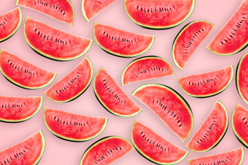 Watermelon cut into small pieces with shell are arranged on pink background.