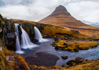 Cascada en otoño con montaña de fondo y cielo dramático