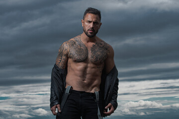 Portrait of handsome man. Naked male shoulders, topless athletic body. Fashion male model with leather jacket.