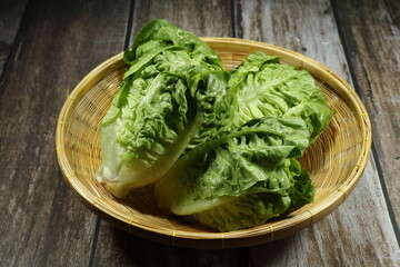 Pile of fresh and organic Romaine lettuce serving on wooden basket. Mock up of product in the market. 