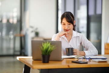 Shot of an Asian young businesswoman working on laptop in her workstation.