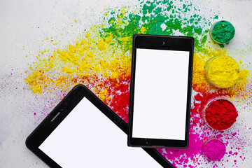 Concept of Indian festival Holi, multi color's on floors with phone and tablet