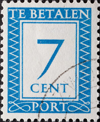 Netherlands - circa 1947: a postage stamp from the Netherlands , showing a number with an ornamental border. In blue.Text: The postage has been paid. Postage due . 7 cent