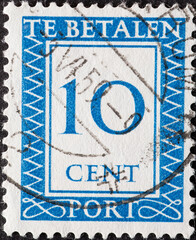 Netherlands - circa 1947: a postage stamp from the Netherlands , showing a number with an ornamental border. In blue.Text: The postage has been paid. Postage due . 10 cent