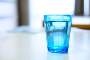 テーブルに置いてある水の入った青いグラス