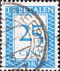 Netherlands - circa 1947: a postage stamp from the Netherlands , showing a number with an ornamental border. In blue.Text: The postage has been paid. Postage due . 25 cent