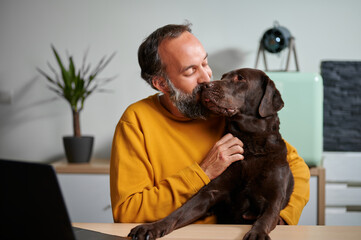 Mature freelancer kissing and hugging dog
