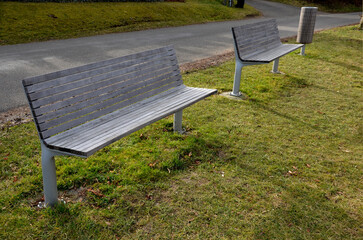 rows of reddish wood benches on their paneling under the benches is a rectangle of concrete anti-scraping beige paths by the shoes of visitors flowering romantic flower beds and lawns
