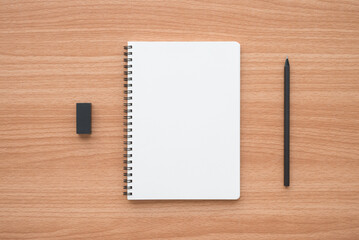 Blank empty ring binder notepad, pencil and black eraser on wooden table background copy space minimal style. Education, back to school or creative idea design concept.