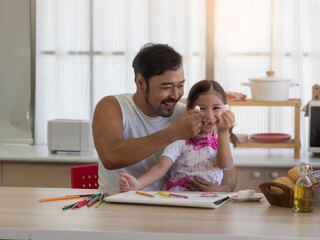 Obraz na płótnie Canvas Asian father playing with daughter eating marshmallow together in the kitchen. Spending quality time Single parent, father's day or homeschooling concept.