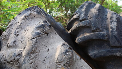 Big tires wear out. Old big tires of a broken heavy machine and torn treads on a green tree background. Close-up focus