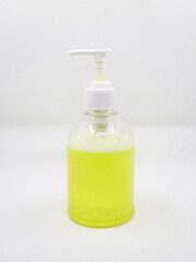 press type soap dispenser with yellow soap solution for cleaning hands used in washrooms isolated in a white background