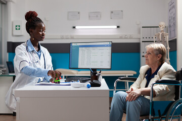 Pensioner invalid senior woman in wheelchair discussing sickness diagnosis with therapist doctor...
