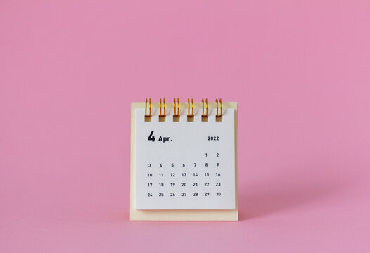 Desktop calendar for April 2022 on a pink background.
