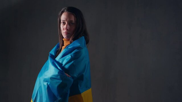 Sad woman covering with Ukrainian flag. Concept of standing with Ukrainian nation in war with Russia.