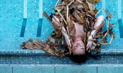 Top view of a beautiful sexy woman with vitiligo disease relaxed in dried up leaves, of a banana...