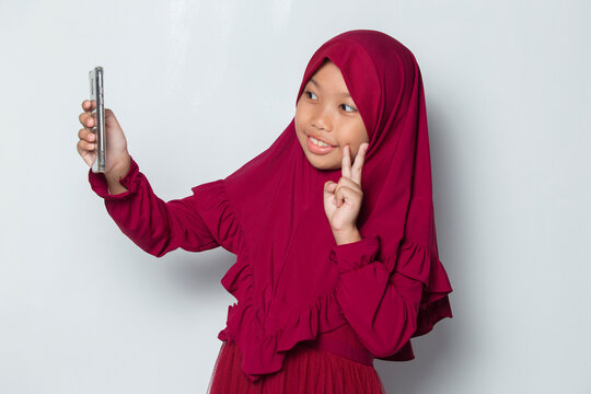 Happy Muslim Asian Little Girl Using Smart Phone Selfie On White Background
