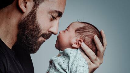 portrait of man looking at his newborn son with loving expression - obrazy, fototapety, plakaty