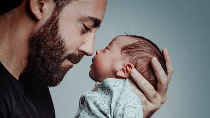 Fototapeten portrait of man looking at his newborn son with loving expression © EvaHM